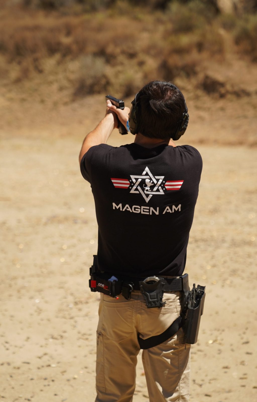 A person shooting in a Magen Am t-shirt.